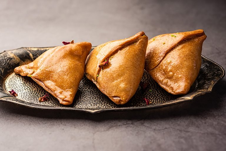 Indian sweet samosa is a Fried pastry soaked in sugar syrup filled with coconut, nuts and fruits